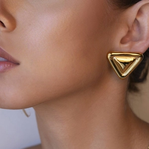 Nahaufnahme eleganter goldener Dreiecksohrringe, getragen von einem Modell für Stil