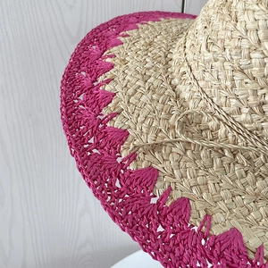 Détail d'un chapeau de soleil en raphia tissé main avec bord ondulé magenta vif