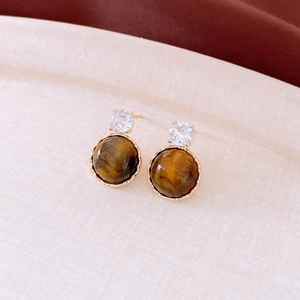 Détail de boucles d'oreilles en œil de tigre plaqué or 18 carats avec pierre facettée