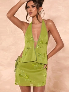 Green sequined two-piece set featuring a halter backless top and matching mini skirt