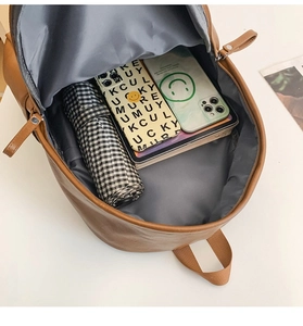 Top view of large capacity brown leather backpack interior holding tablet and umbrella