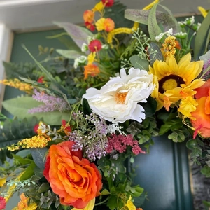 Colorful summer wreath with yellow sunflowers, orange roses and eucalyptus for door decor
