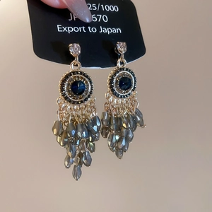 Close-up of Bohemian silver needle earrings with blue crystal beads and tassels