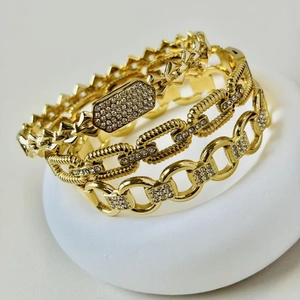 Detail shot of three layered gold bracelets with pave rhinestones and chain links