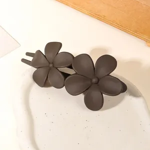 Macro detail of brown matte floral hair clip with double-flower design on a tray