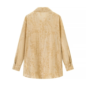 Detail of vertical pleated texture and delicate floral embroidery on beige shirt back