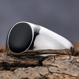 Minimalist silver stainless steel signet ring with black oval enamel inlay on wood texture