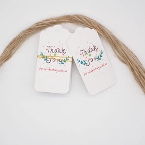 Close-up of white floral thank you tags with natural twine on plain white background