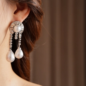 Macro detail of silver pearl earrings with sparkling crystals on female model