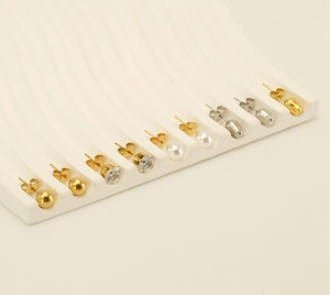 Close-up of gold and silver ball, pearl and crystal studs on a white display wave