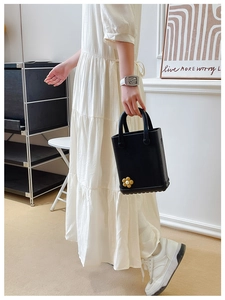 Detail der schwarzen EVA-Lochtasche mit Blumendeko getragen zu einem weißen Sommerkleid