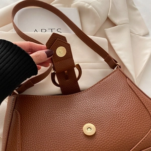 Close-up of brown lychee grain leather underarm bag featuring gold metallic buckle details