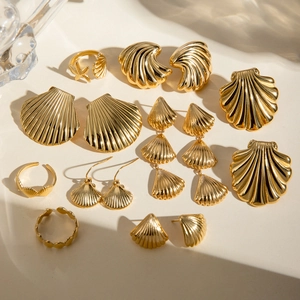 Detailed set of gold seashell earrings and starfish rings on beige background