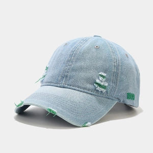 Gros plan détaillé sur casquette en jean délavé avec broderie 1999 verte et bords effilochés