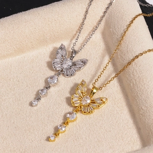 Exquis colliers pendentifs papillon en or et argent avec pompons sur présentoir beige