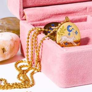 Macro shot of 18K gold plated bunny tarot necklace pendant in a pink velvet box