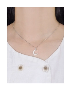 Close-up of a crescent moon pendant with textured surface on a silver necklace
