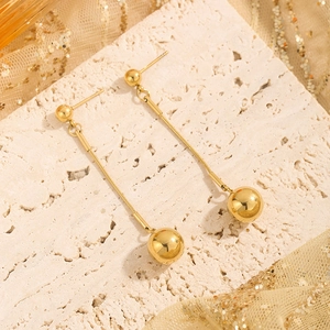 Gold French ball drop earrings with snake chain and round pendant on light stone background