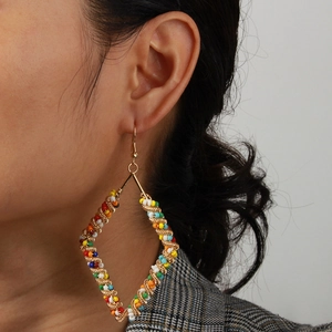 Detailed side view of large bohemian rhombus earrings with colorful beads and gold wire