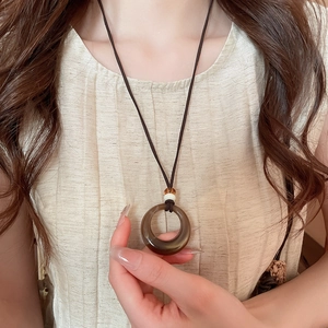 Gros plan d'un pendentif anneau en acrylique ambré sur un cordon tressé marron foncé