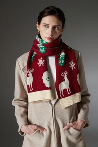 Detailed close-up of festive red knit scarf with white reindeer and snowflake patterns