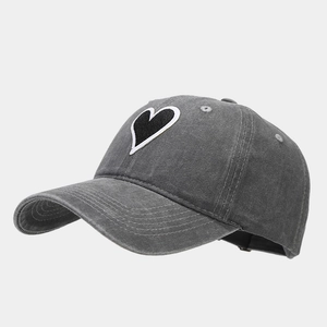 Close-up of heart embroidery patch and washed vintage texture on dark grey baseball cap
