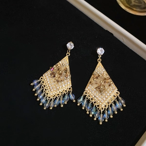 Macro detail of diamond-encrusted rhombic earrings with iridescent waterdrop tassels