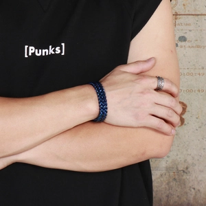 Blue woven double keel stainless steel bracelet and silver ring on a male model arm