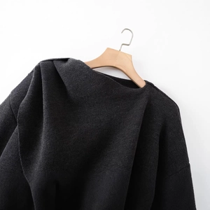 Minimalist knit poncho sweater with scarf on wooden hanger against white background