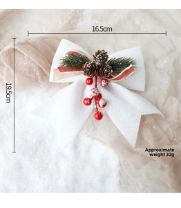 White glitter Christmas bow with pine cones and red berries measuring 16.5cm by 19.5cm