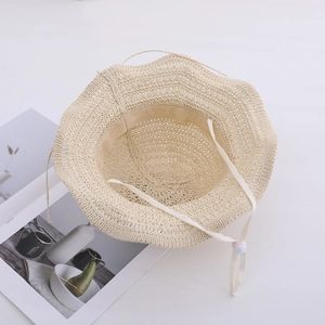 Detail of beige woven straw hat with wavy brim, mesh knit pattern and adjustable chin strap