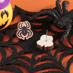 Close-up of wooden spider stud earrings with purple accents on black spider web background
