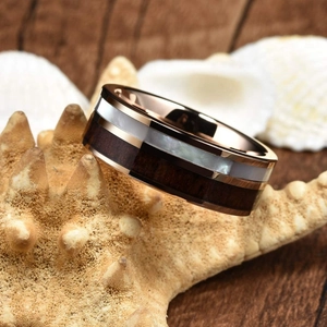 Detail of rose gold ring with wood and shell inlay resting on a starfish