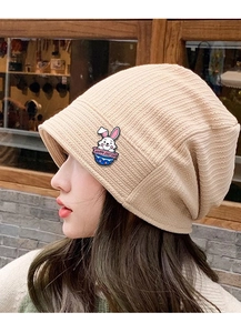 Detail of cute rabbit badge accessory pinned on a beige knitted beanie hat for Easter