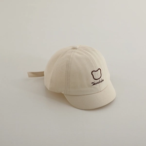 Détail de la casquette bébé beige avec broderie ours mignon et texture à bord souple