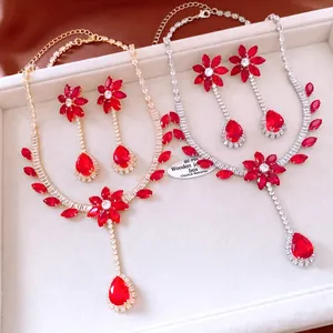 Close-up of red gemstone flower necklace and earring sets in gold and silver finishes