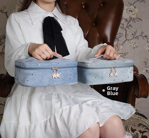 Close-up of a grey blue velvet toiletry bag with gold star patterns and a star-shaped zipper
