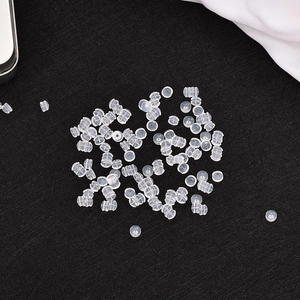 Scattered clear plastic bullet clutch earring safety backs on a textured black surface
