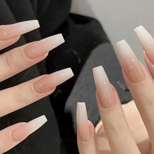 Macro shot of long coffin shaped press-on nails with nude pink to white gradient finish