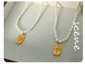 Detailed close-up of freshwater pearl necklace with vintage gold tulip relief pendant