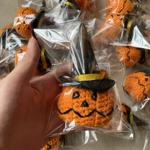 Detailed close-up of a handmade crochet Halloween pumpkin doll with a black wizard hat