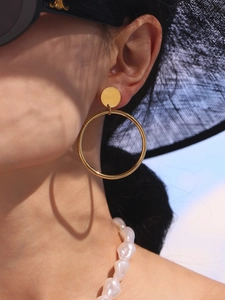Créoles chic en acier inoxydable plaqué or 18k portées avec un chapeau de paille noir chic