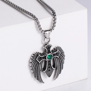 Detailed view of a vintage angel wing cross pendant with a green zircon on a box chain