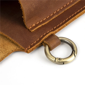 Detail of vintage brown leather pouch showing stitching and bronze metal ring hook