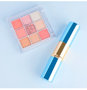 Détail d'une palette d'ombres à paupières 9 couleurs et stick maquillage sur fond bleu clair