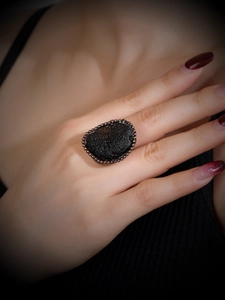 Macro shot of a vintage bronze ring featuring irregular black stone on a hand
