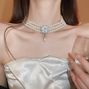 Détail d'un collier de perles multicouche avec boucle fleurie en diamant et pendentif