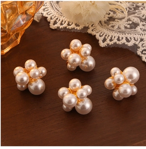 Detailed close-up of pearl cluster earrings with gold base on a vintage wooden surface
