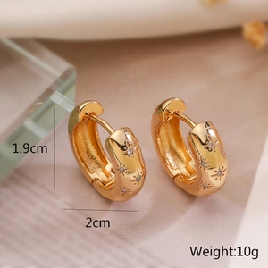 Detailed close-up of gold-plated hoop earrings with star carvings and zircon stones