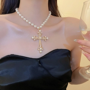 Close-up of pearl necklace with a vintage gold hollow cross pendant and pearl accents